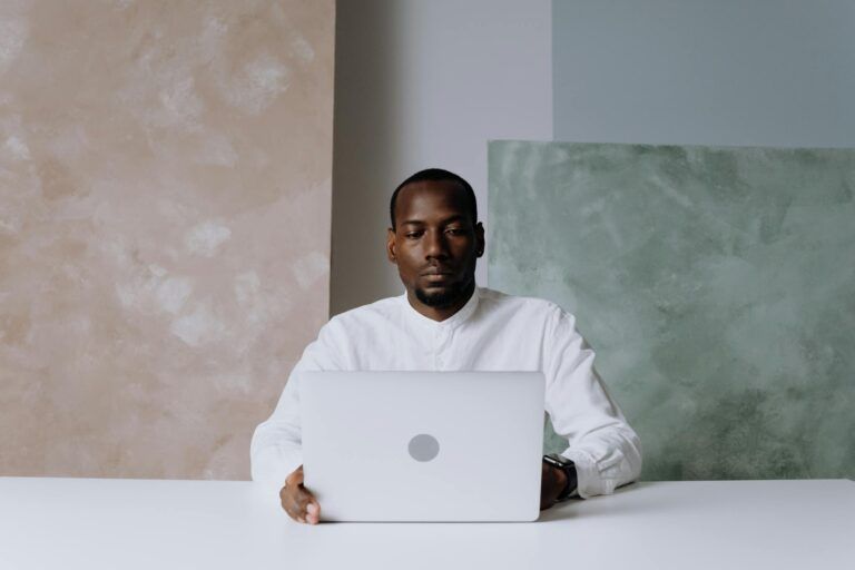 A focused man working intently on his laptop in a modern office setting.
