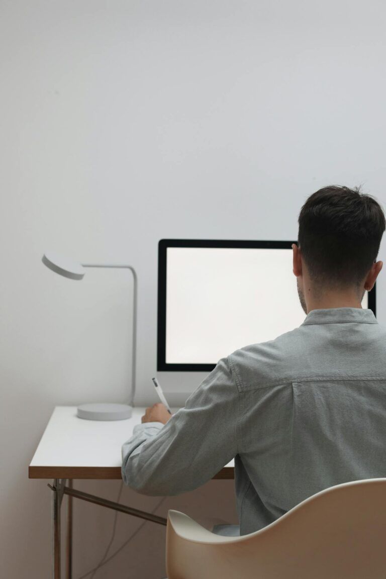 Man working at a minimalist desk with a blank screen, ideal for concept of focus and simplicity.